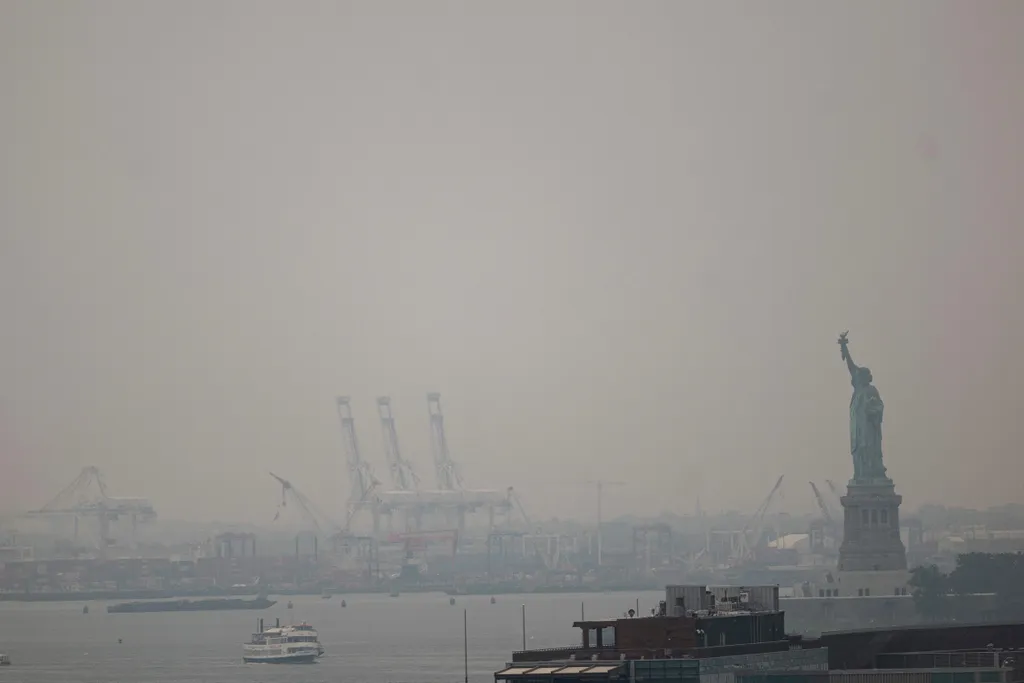 NEW YORK, NEW YORK - JULY 16: Haze from Canadian wildfires blankets the Statue of Liberty as seen from the Brooklyn Bridge on July 16, 2026 in New York City. Much of the East Coast and Canada is under an Air Quality Health Advisory as the Canadian and Great Lakes wildfire smoke gradually moves through the area, creating a thick haze in the heat. The region is experiencing temperatures with heat indexes over 100 degrees as it confronts another heat wave. Spencer Platt/Getty Images/AFP (Photo by SPENCER PLATT / GETTY IMAGES NORTH AMERICA / Getty Images via AFP)