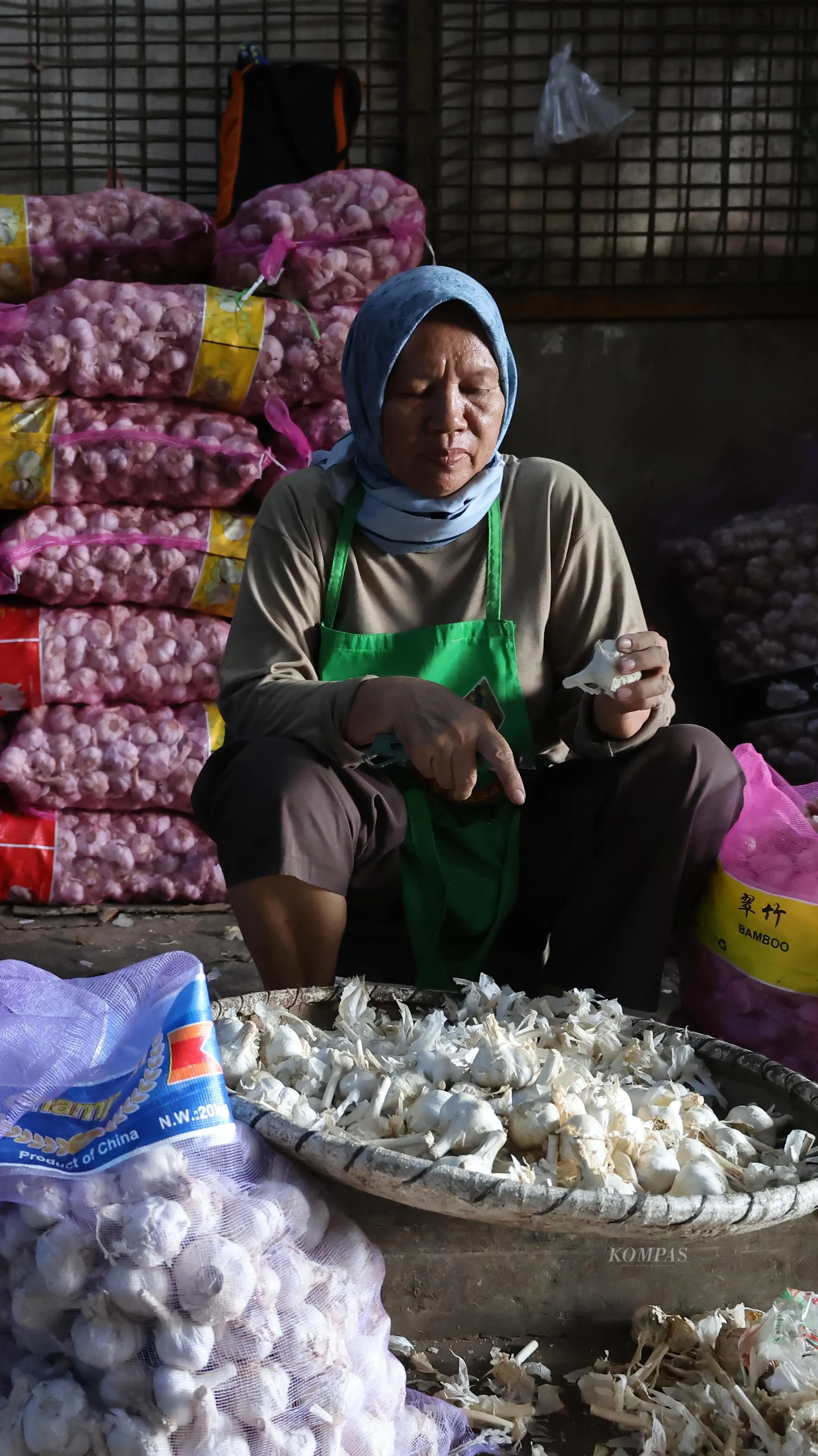 <p>Pon mengupas bawang putih di Pasar Induk Kramat Jati.</p><p>KOMPAS/TOTOK WIJAYANTO</p>